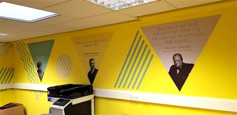 An image of triangular wall graphics with a person's image and quote in each.